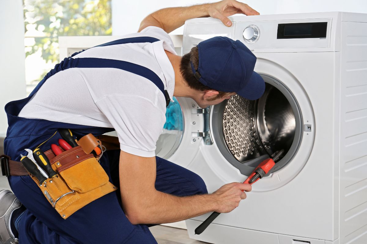 laki-laki memperbaiki mesin cuci